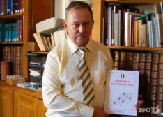 Un homme tenant un livre devant une étagère. Un homme tenant un livre devant une étagère.